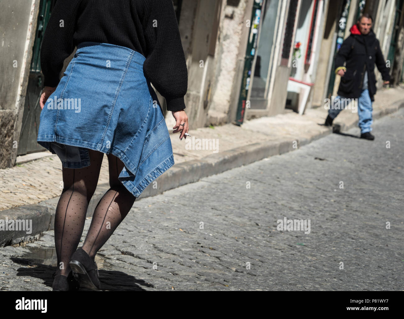 Donna che cammina per una strada di ciottoli, un uomo che sale sulla strada Foto Stock