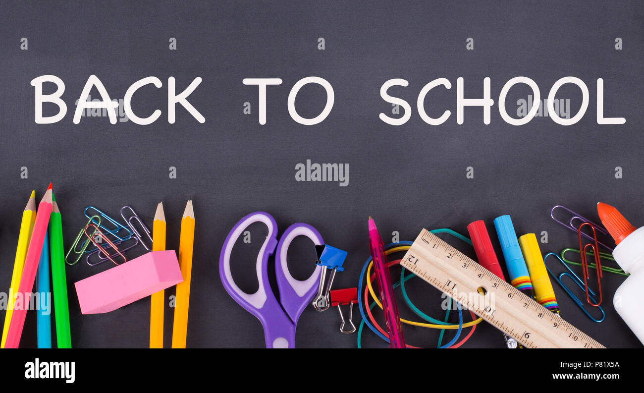 Si torna a scuola il testo scritto su una lavagna con una fila di forniture scolastiche lungo la parte inferiore Foto Stock