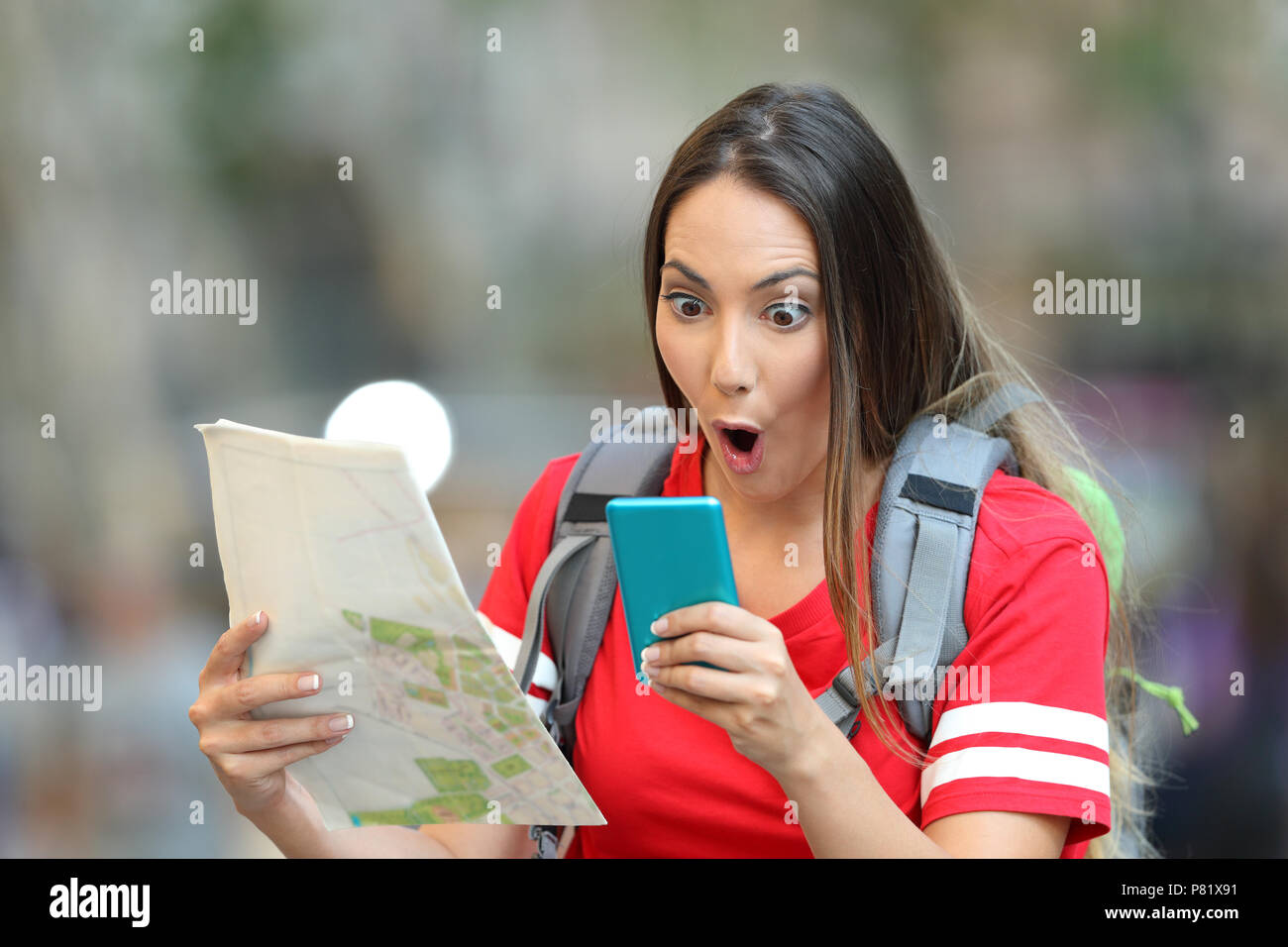Sorpreso teen azienda turistica una mappa e la lettura di contenuti online in uno smart phone su strada Foto Stock