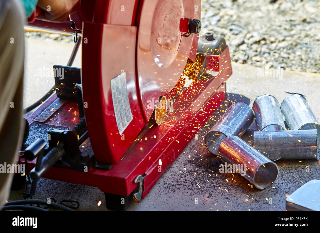 Un lavoratore edile il taglio di un acciaio zincato tubo con una troncatrice troncatrice Foto Stock