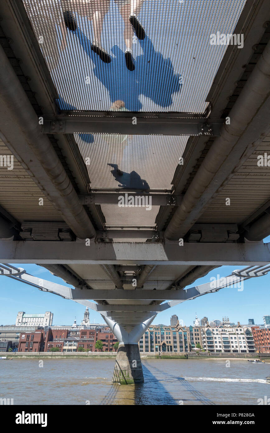 I pedoni a piedi oltre il Millennium Bridge, visto dal basso, attraverso la griglia trasparente Foto Stock