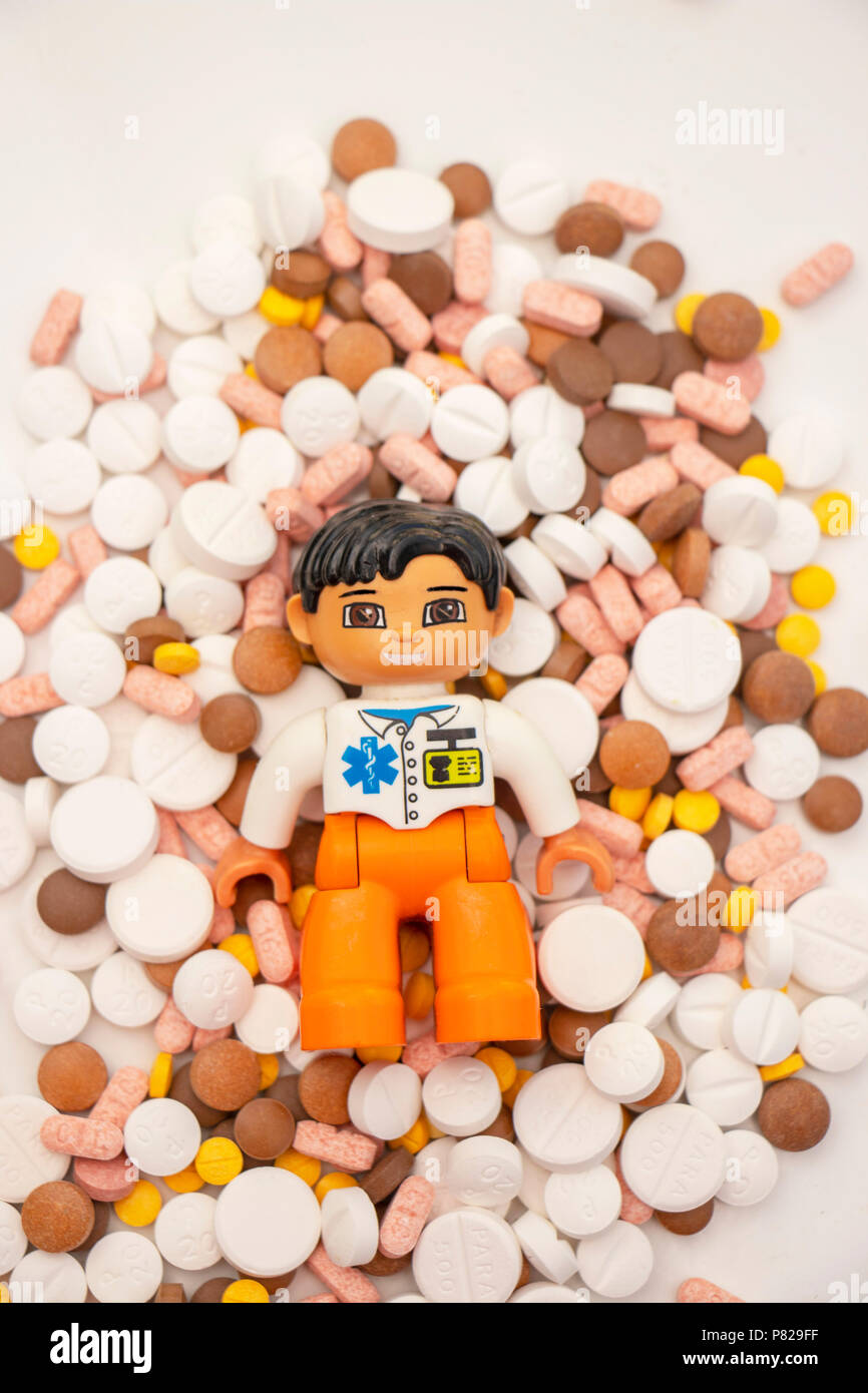 la bambola lego doctor, ripresa concettuale, è circondata da un mucchio di pillole e farmaci che raffigurano la crisi dell'oppiaceo da prescrizione Foto Stock