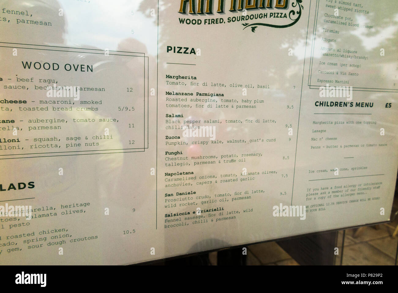 Un menu con i prezzi di pizza e di altri prodotti alimentari italiani /  pasto / i pasti nella finestra di una pizzeria con forno a legna.  Twickenham, Regno Unito (99 Foto stock - Alamy