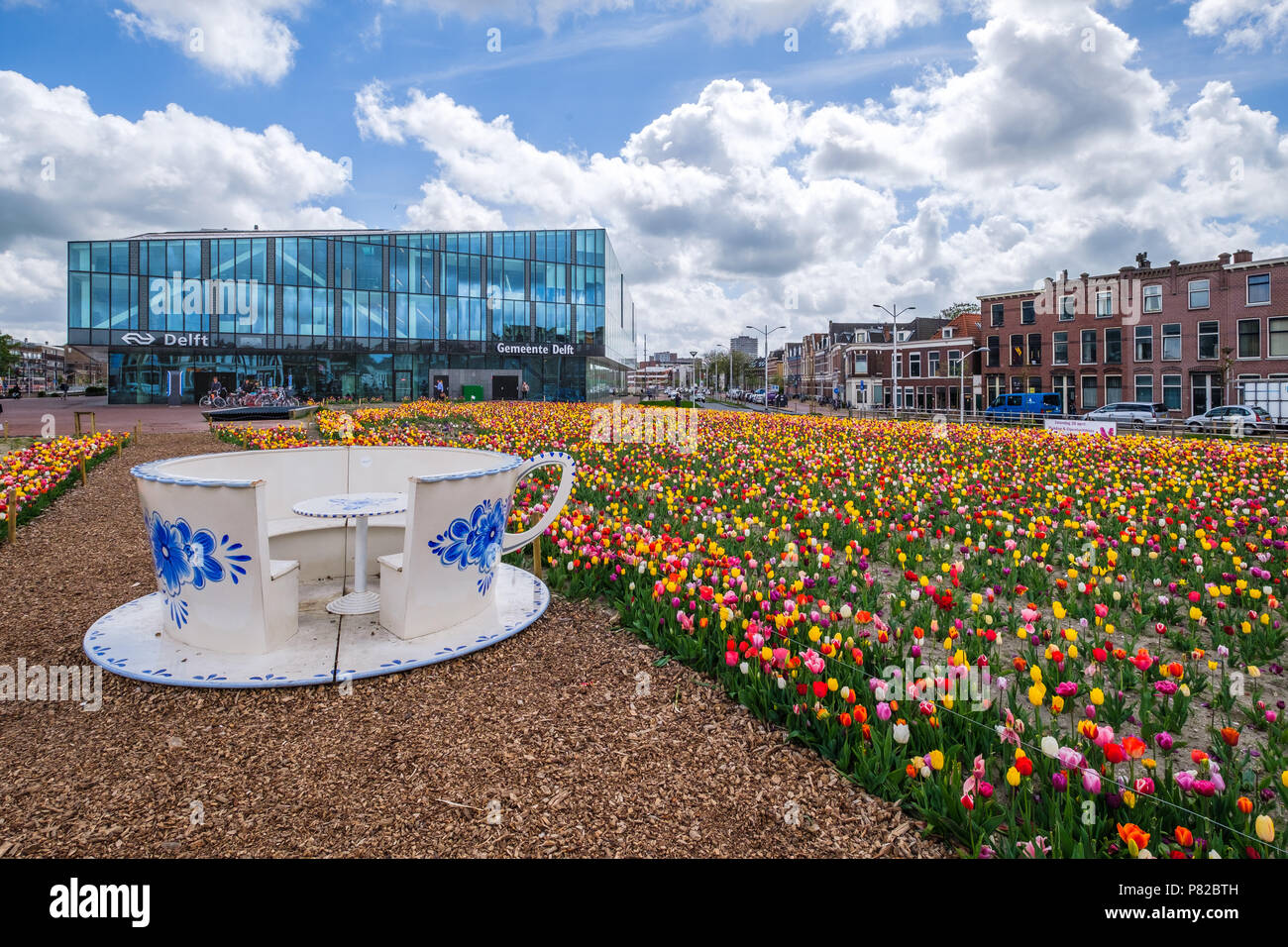 Un tulipano giardino antistante il municipio nuovo / stazione ferroviaria di Delft, Paesi Bassi e davanti a un enorme blu Delft tazza e piattino Foto Stock