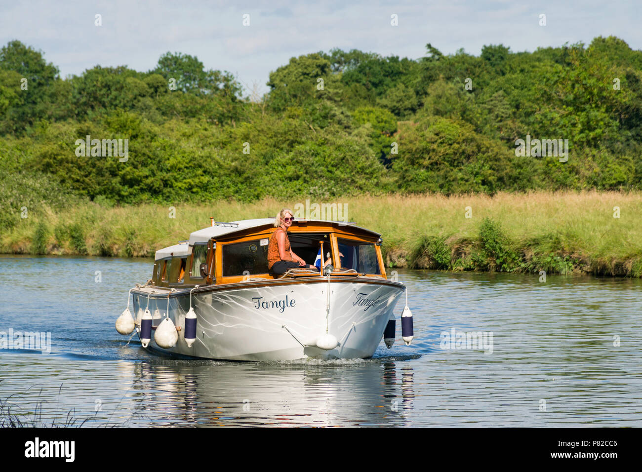 Un incrociatore GRP crociera sul fiume Cam con una donna sat sulla parte anteriore su una soleggiata giornata estiva, Cambridge Foto Stock