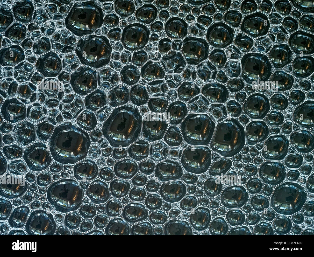 Un primo piano di uno strato di lotti di piccole bolle di sapone galleggiante sull'acqua Foto Stock