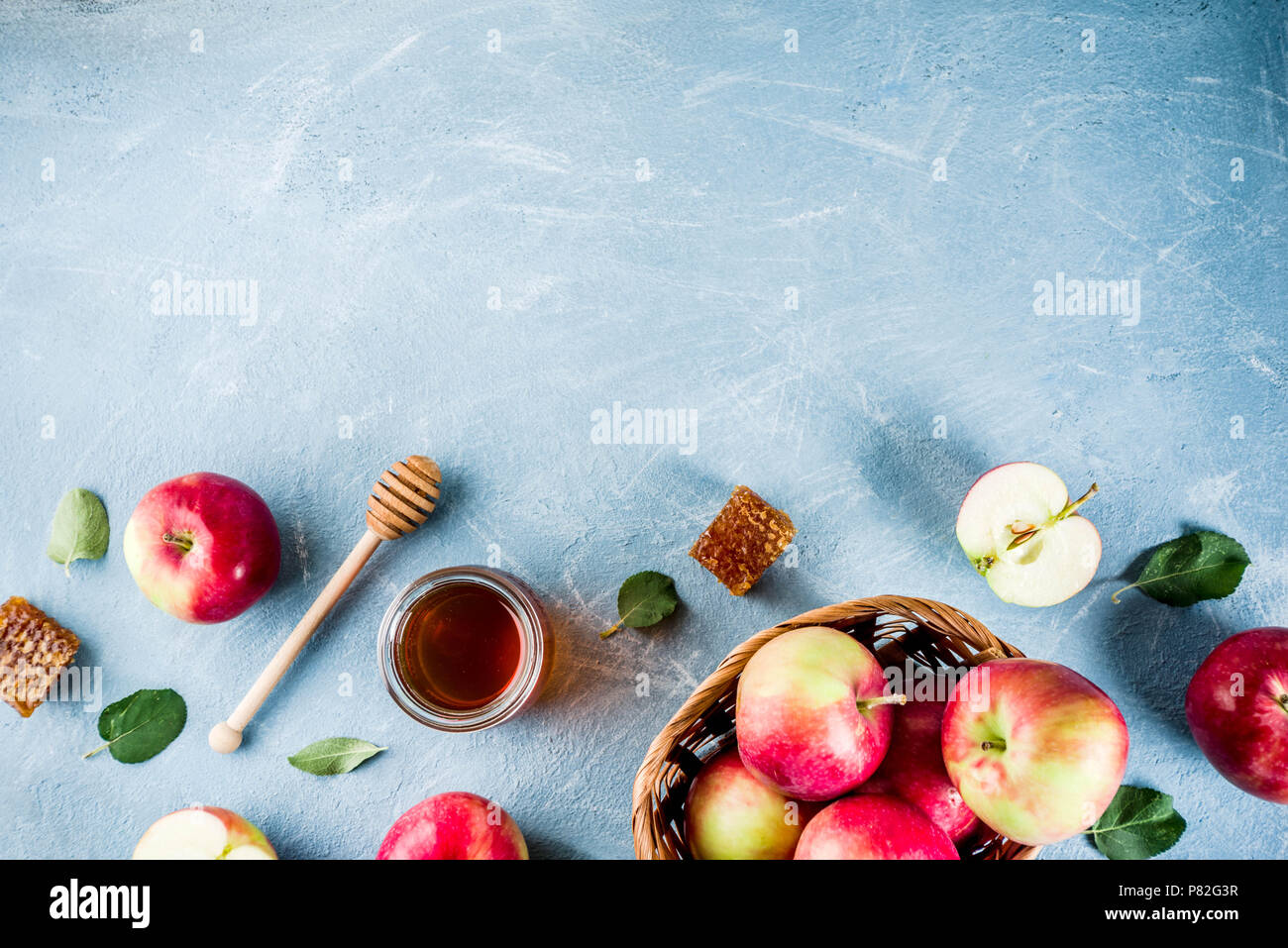 Festa ebraica di Rosh Hashanah o apple festa concetto, con le mele rosse, foglie di apple e il miele in barattolo, luce sfondo blu copia spazio sopra Foto Stock