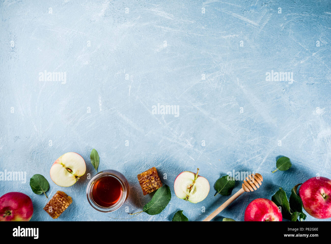 Festa ebraica di Rosh Hashanah o apple festa concetto, con le mele rosse, foglie di apple e il miele in barattolo, luce sfondo blu copia spazio sopra Foto Stock