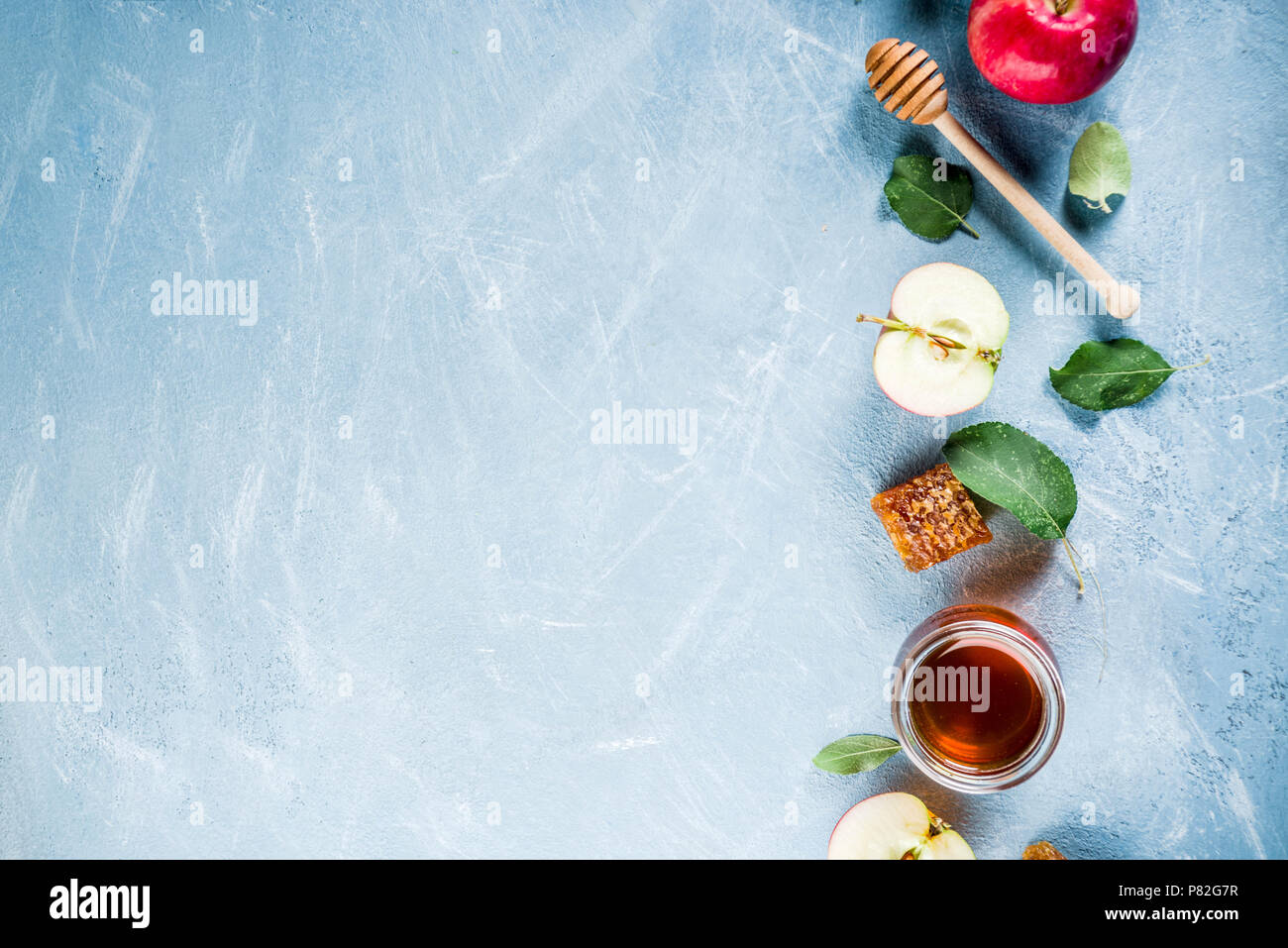 Festa ebraica di Rosh Hashanah o apple festa concetto, con le mele rosse, foglie di apple e il miele in barattolo, luce sfondo blu copia spazio sopra Foto Stock