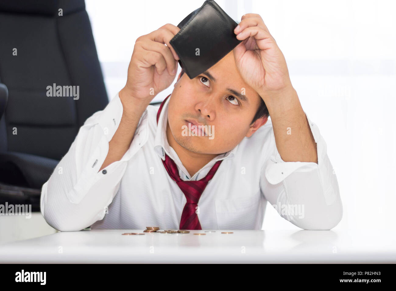 Un fallimento, ha rotto e frustrato uomo sta avendo problemi finanziari con le monete lasciate sul tavolo e un portafoglio vuoto. Foto Stock