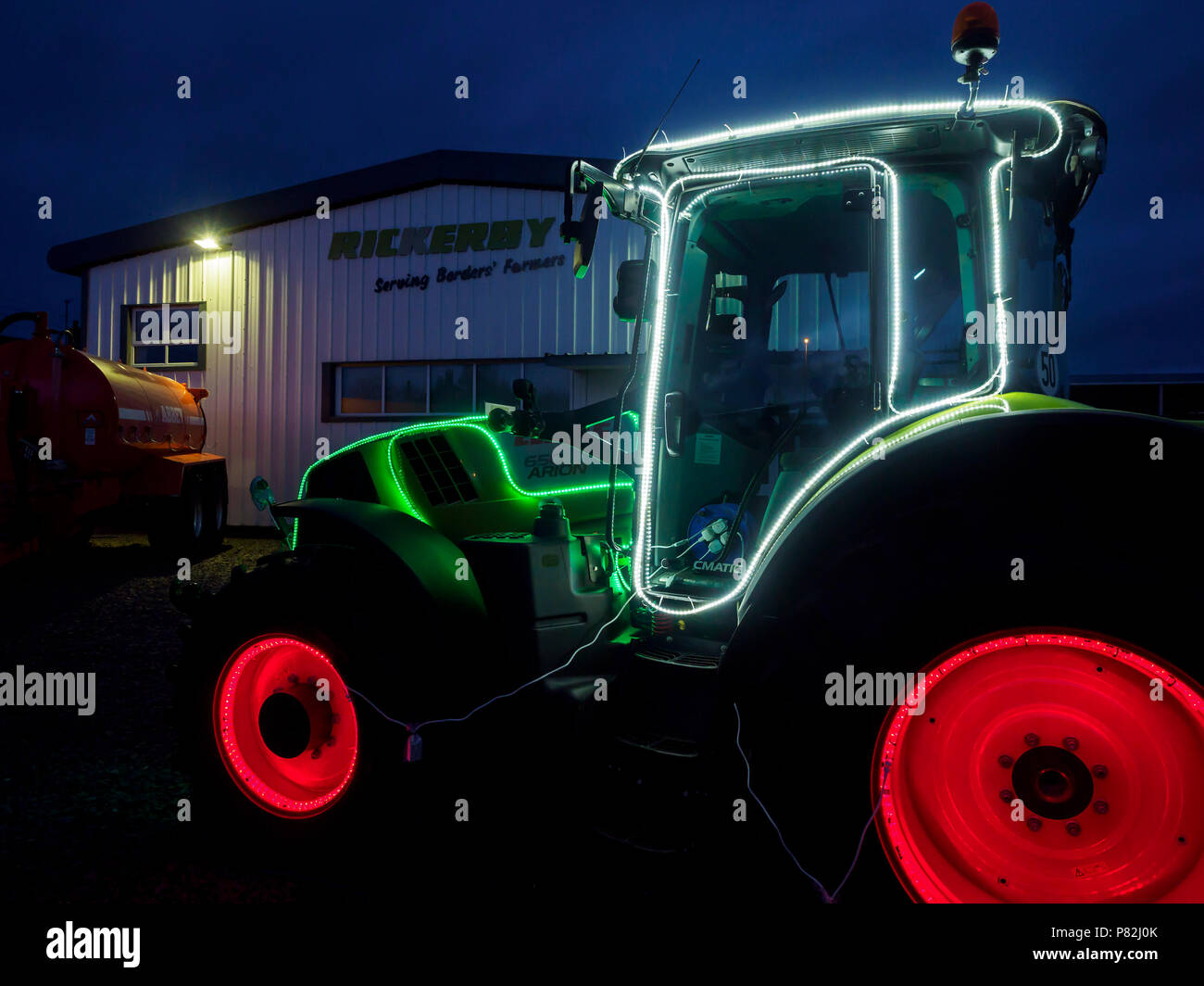 Stagione di Natale pubblicità - in Cornhill in Northumberland, trattore concessionari Riccurby utilizzare strisce LED per decorare un trattore e la cabina sul piazzale. Foto Stock
