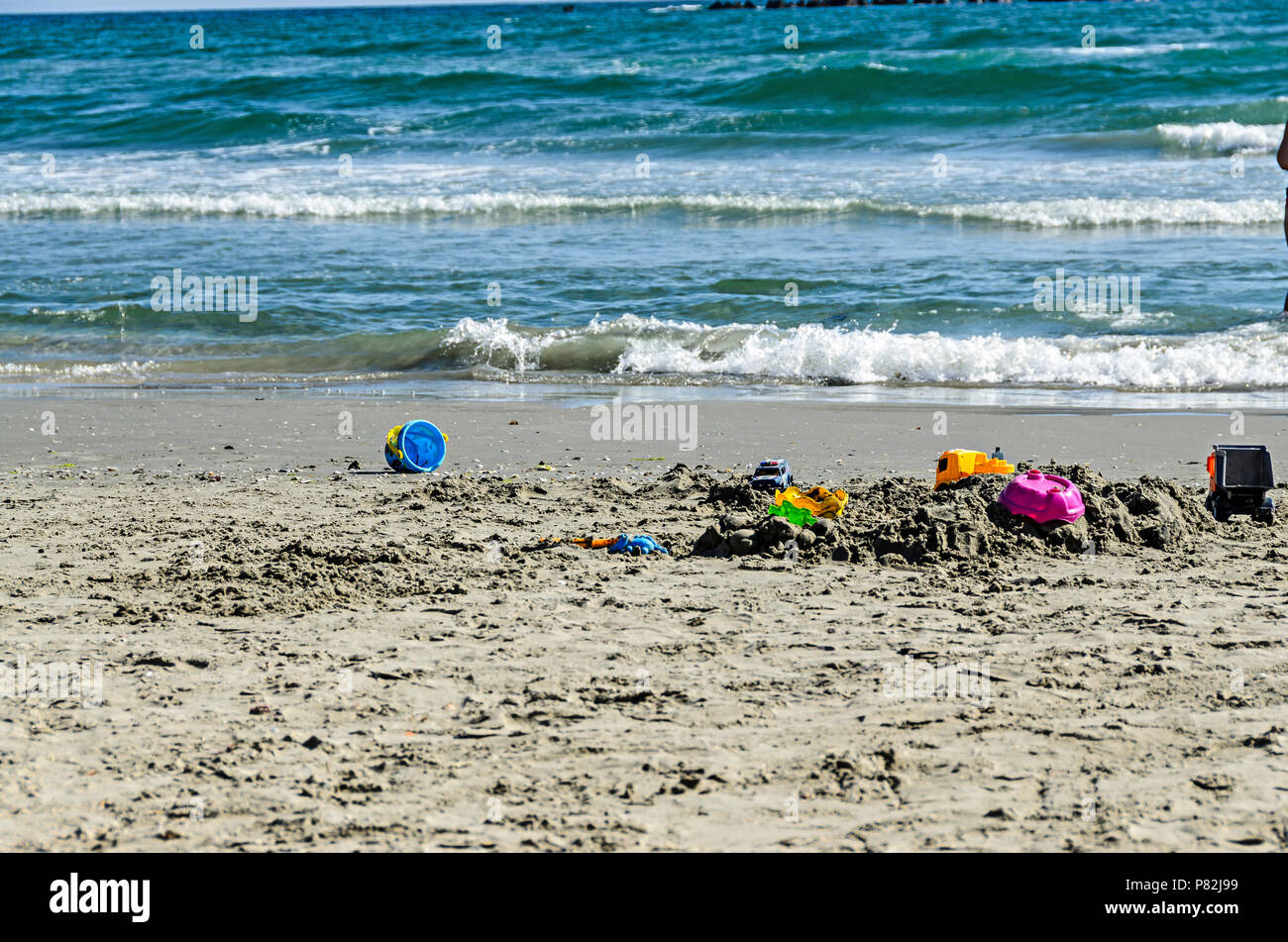 Giocattolo blu benna nella sabbia di mare nei pressi di acque blu e la spiaggia, Mar Nero a riva. Foto Stock