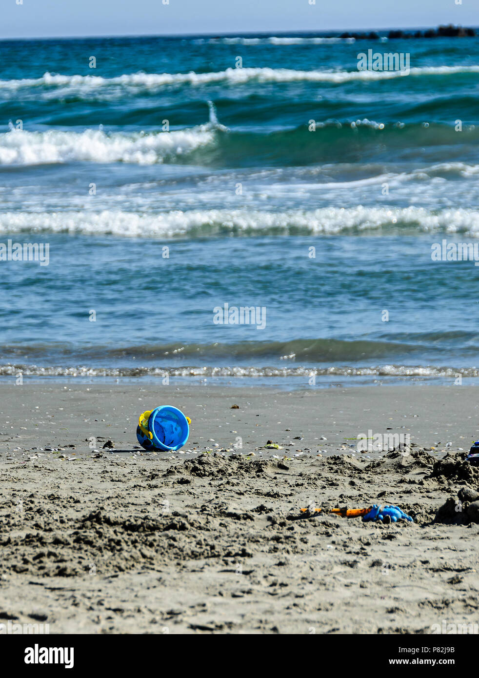 Giocattolo blu benna nella sabbia di mare nei pressi di acque blu e la spiaggia, Mar Nero a riva. Foto Stock