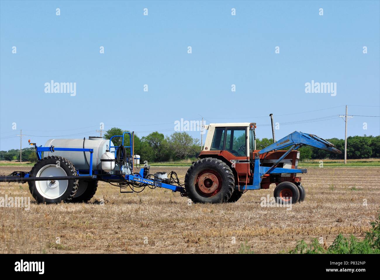 Trattore agricolo con spruzzatore in un campo con il blu del cielo. Foto Stock