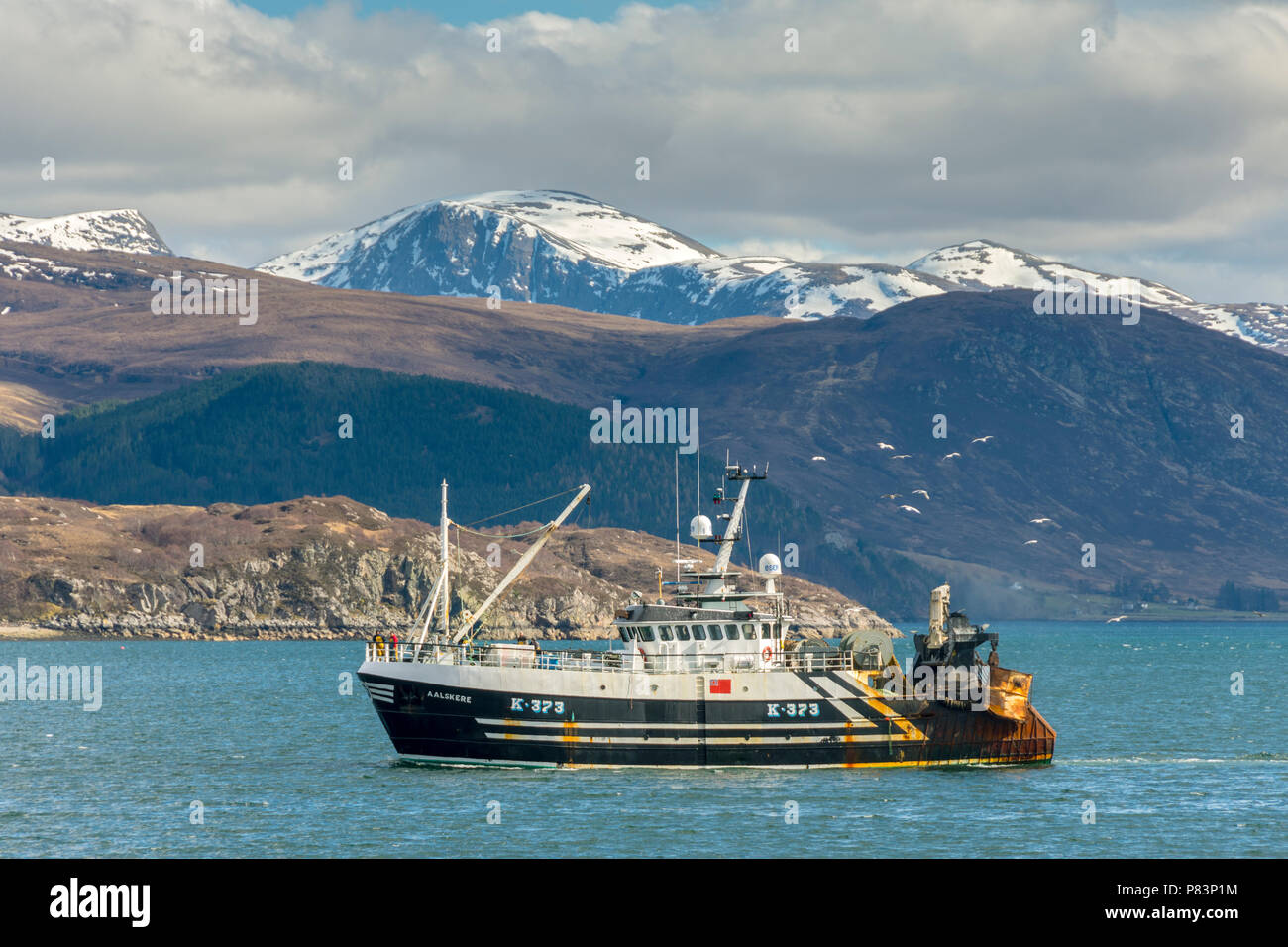 Una barca da pesca in avvicinamento al porto di Ullapool sul Loch scopa con la Beinn Dearg mountain range dietro. Ullapool, Sutherland, Scotland, Regno Unito Foto Stock