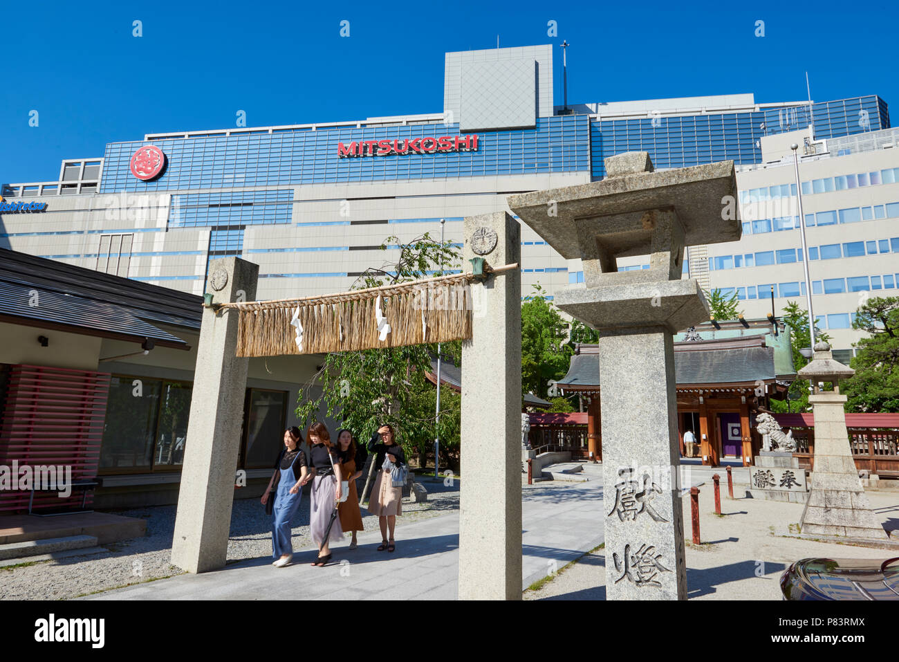 Bassa angolazione delle lanterne giapponesi nel Santuario Kego con negozio di moderni edifici in background. In Tenjin, central Fukuoka, Giappone Foto Stock