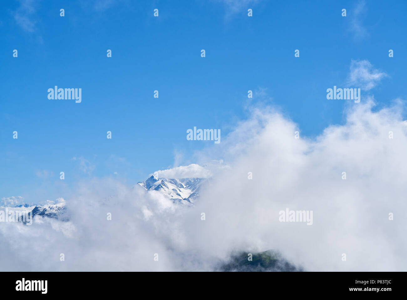 Le nuvole nel cielo blu sopra le montagne con la neve nelle Alpi Foto Stock