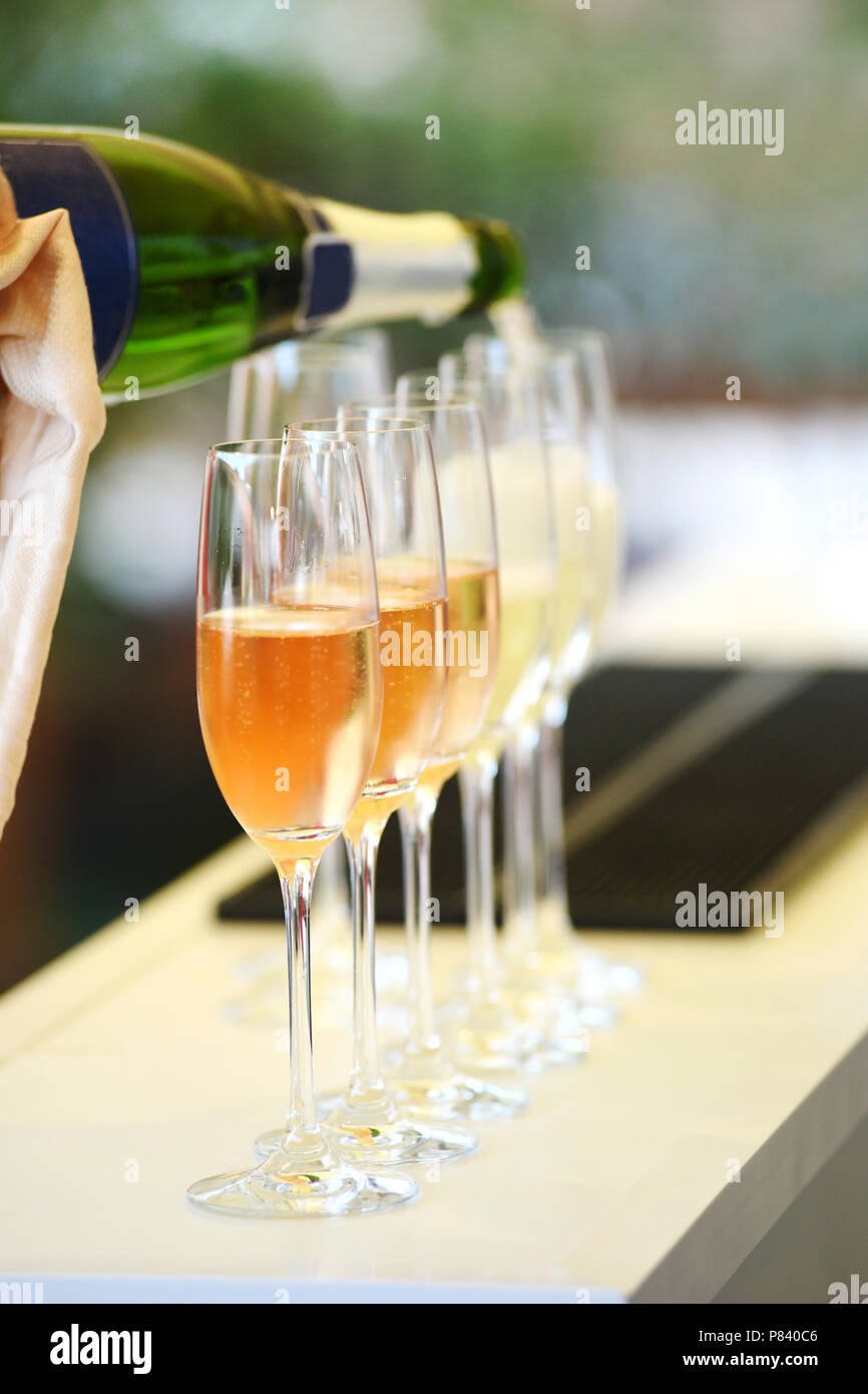 Versando il prosecco in bicchieri in piedi in fila Foto Stock