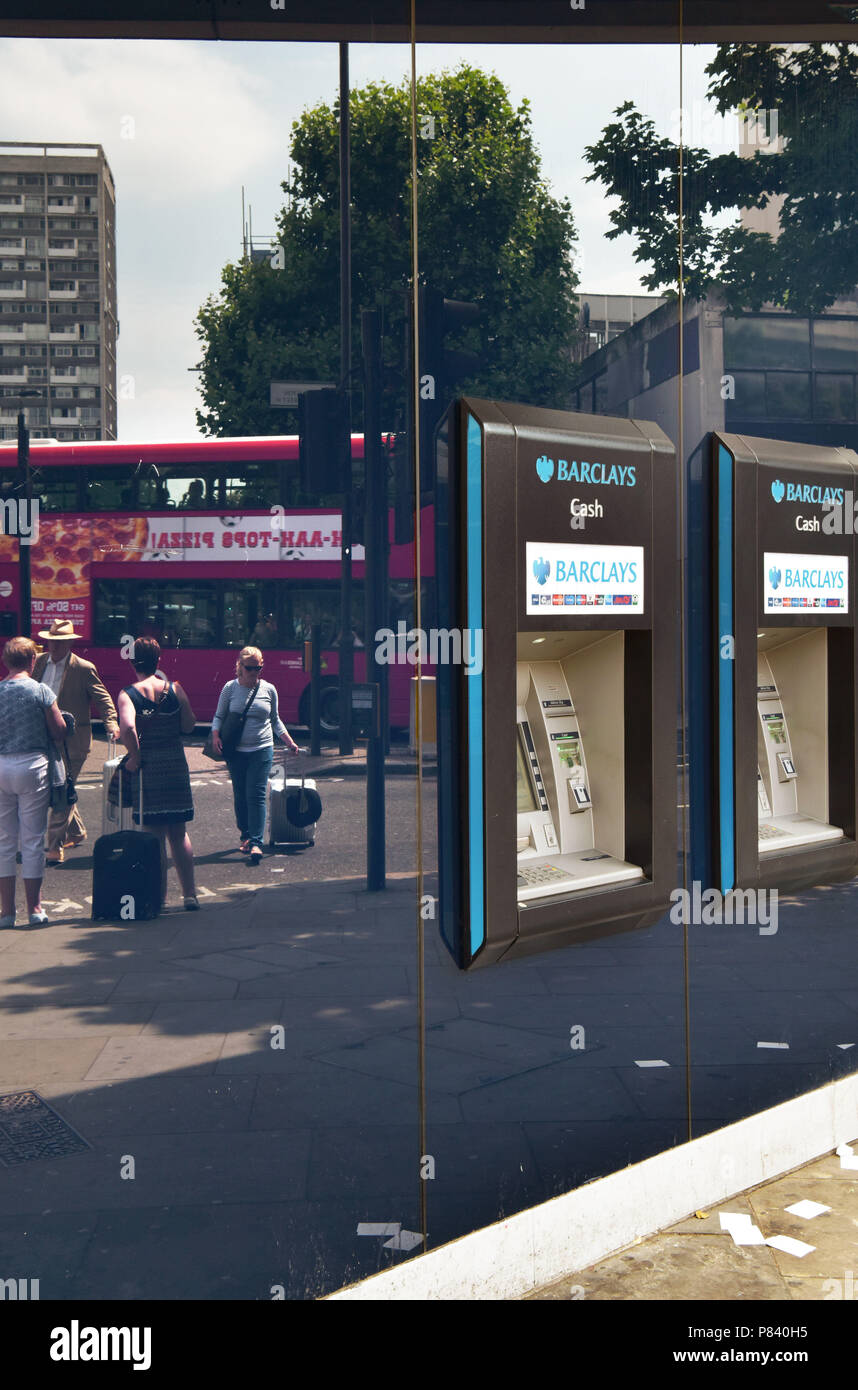 Le persone si riflette nella finestra, a piedi passato la banca Barclays ATM in Notting Hill, Londra. Foto Stock