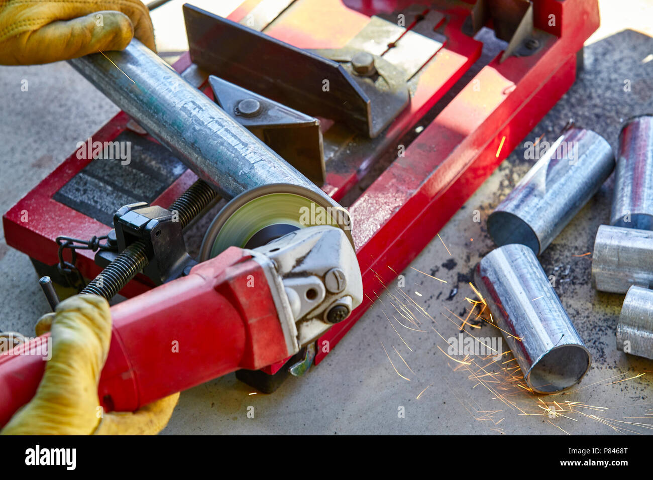 Un lavoratore edile utilizzando una smerigliatrice su un nuovo taglio della lamiera zincata tubo in acciaio Foto Stock