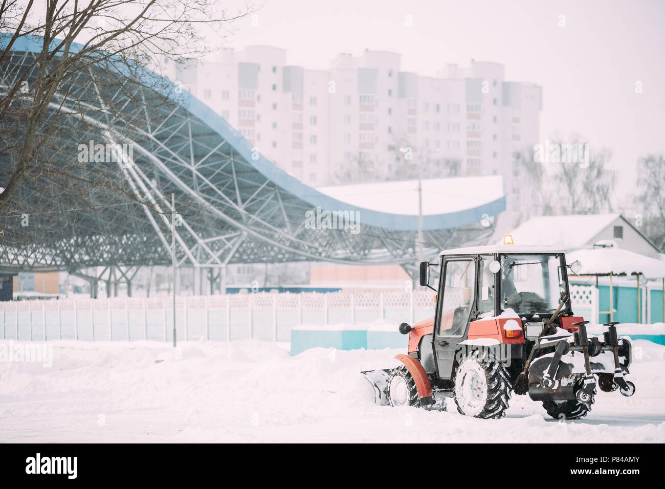 Pulizia del trattore la neve in inverno nevoso giorno tempesta di neve in città. Foto Stock