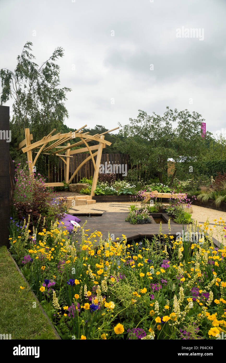 Fiori colorati, pergola in legno, da banco e da stagno in bella prize-winning giardino, i grandi spazi aperti - RHS Chatsworth Flower Show, Inghilterra, Regno Unito. Foto Stock