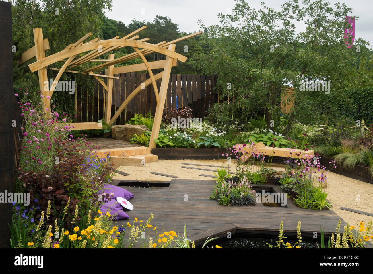 Fiori colorati, pergola in legno, da banco e da stagno in bella prize-winning giardino, i grandi spazi aperti - RHS Chatsworth Flower Show, Inghilterra, Regno Unito. Foto Stock