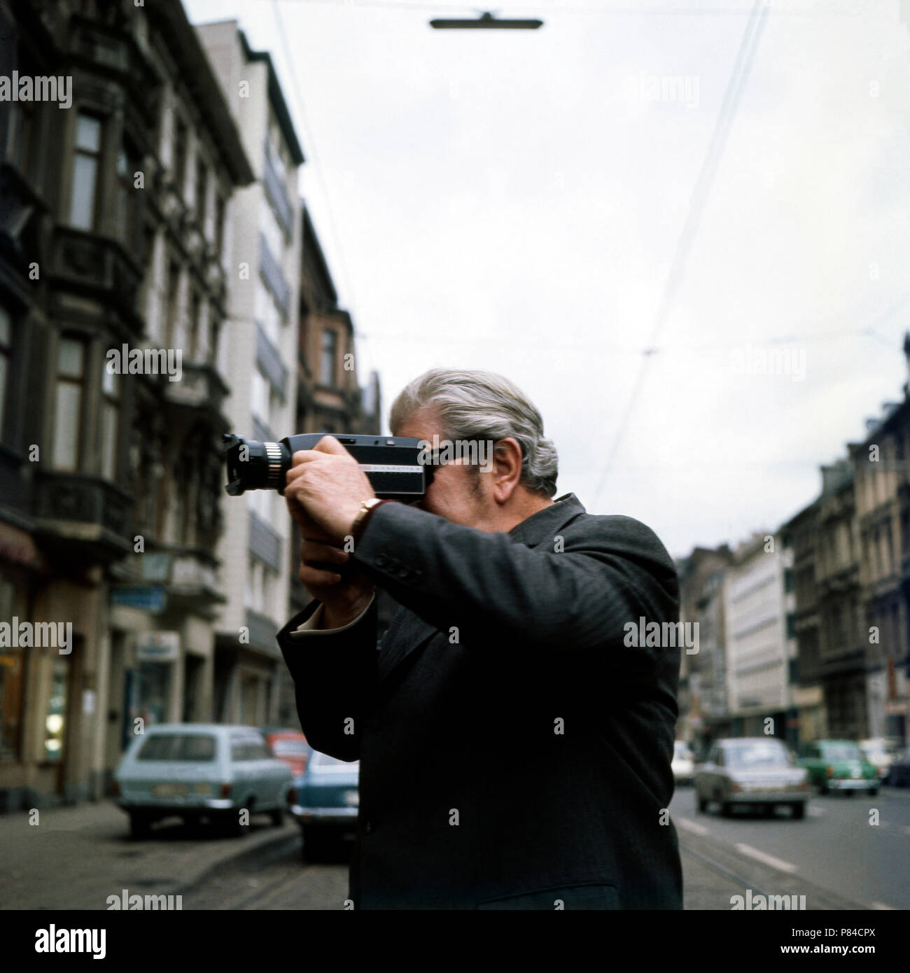 Volksschauspieler Willy Millowitsch steht auf der Aachener Straße in Köln und filmt mit circuizione Super8-Kamera sein Theatre, Deutschland 1973. Folklore attore Willy Millowitsch prendendo un super 8 film del suo teatro nel centro della città di Colonia, Germania 1973. Foto Stock