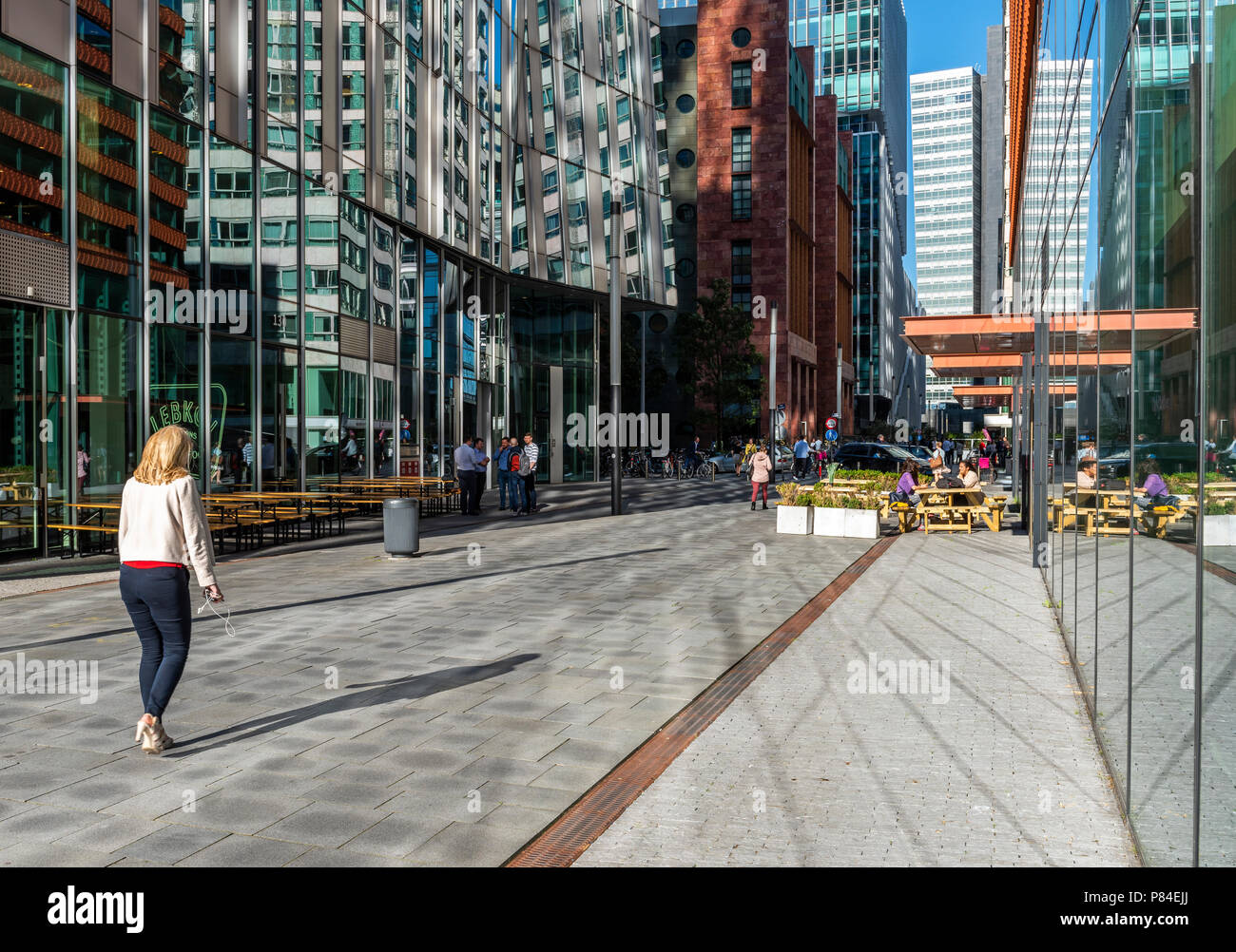 Amsterdam, Paesi Bassi - 20 Giugno 2018: Donna con lo smartphone sul Amsterdam Zuidas, Paesi Bassi, con alti edifici di uffici. Foto Stock