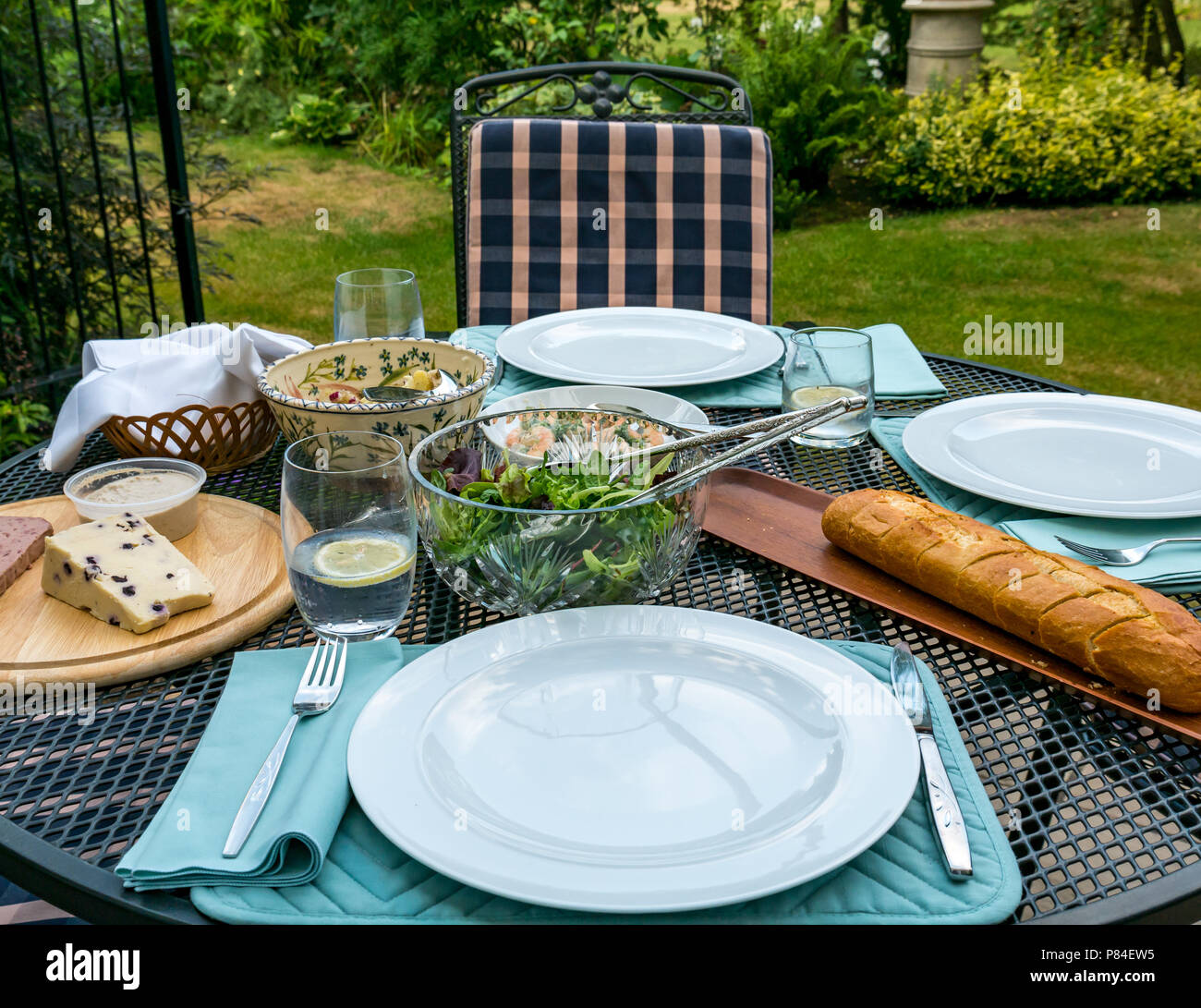 Il giardino esterno patio tabella prevista per la cena con insalate, formaggi e pane baguette, London, England, Regno Unito Foto Stock