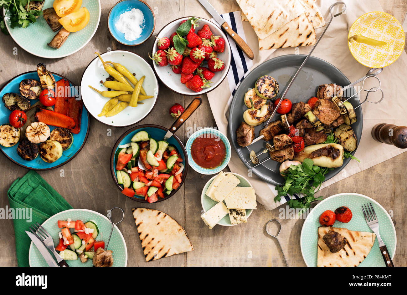 Diversi di cibo per la cottura sulla griglia. Shish kebab, verdure alla griglia, insalate, spuntini e fragole. Tavola di Cena concept Foto Stock