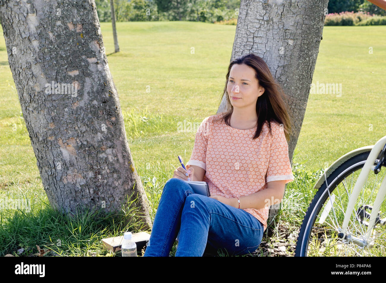 Bella donna spensierata seduto sotto un albero godendo il momento Foto Stock