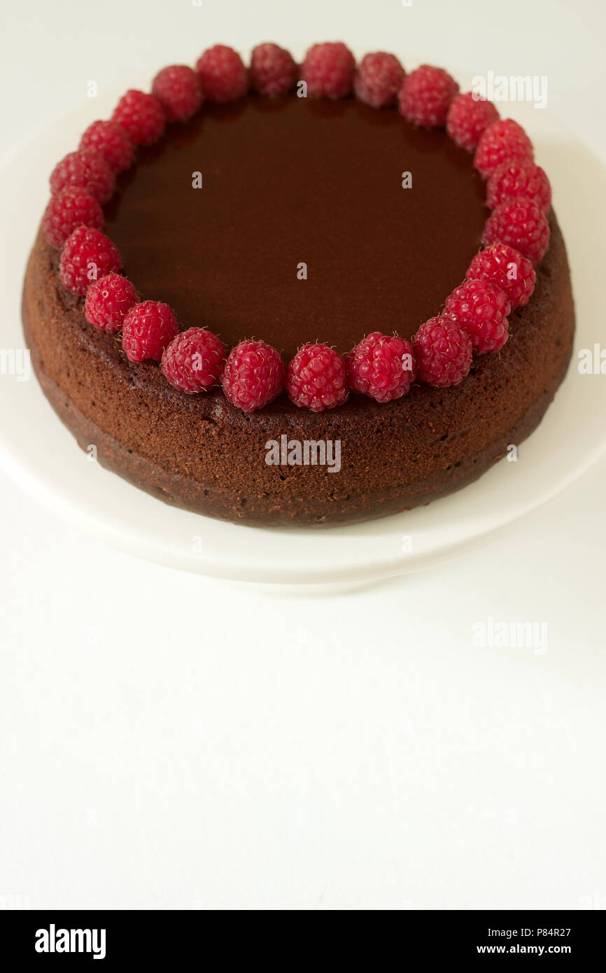 Brownie al cioccolato torta con lamponi e glassa di cioccolato su uno sfondo luminoso. Messa a fuoco selettiva. Foto Stock