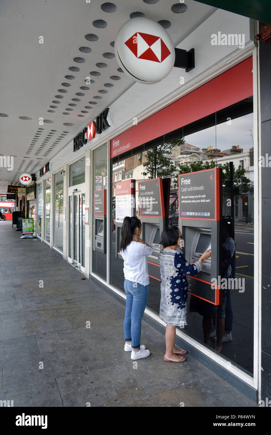 Un cliente utilizza il bancomat al di fuori della Banca filiale della HSBC a Notting Hill, Londra centrale. Foto Stock