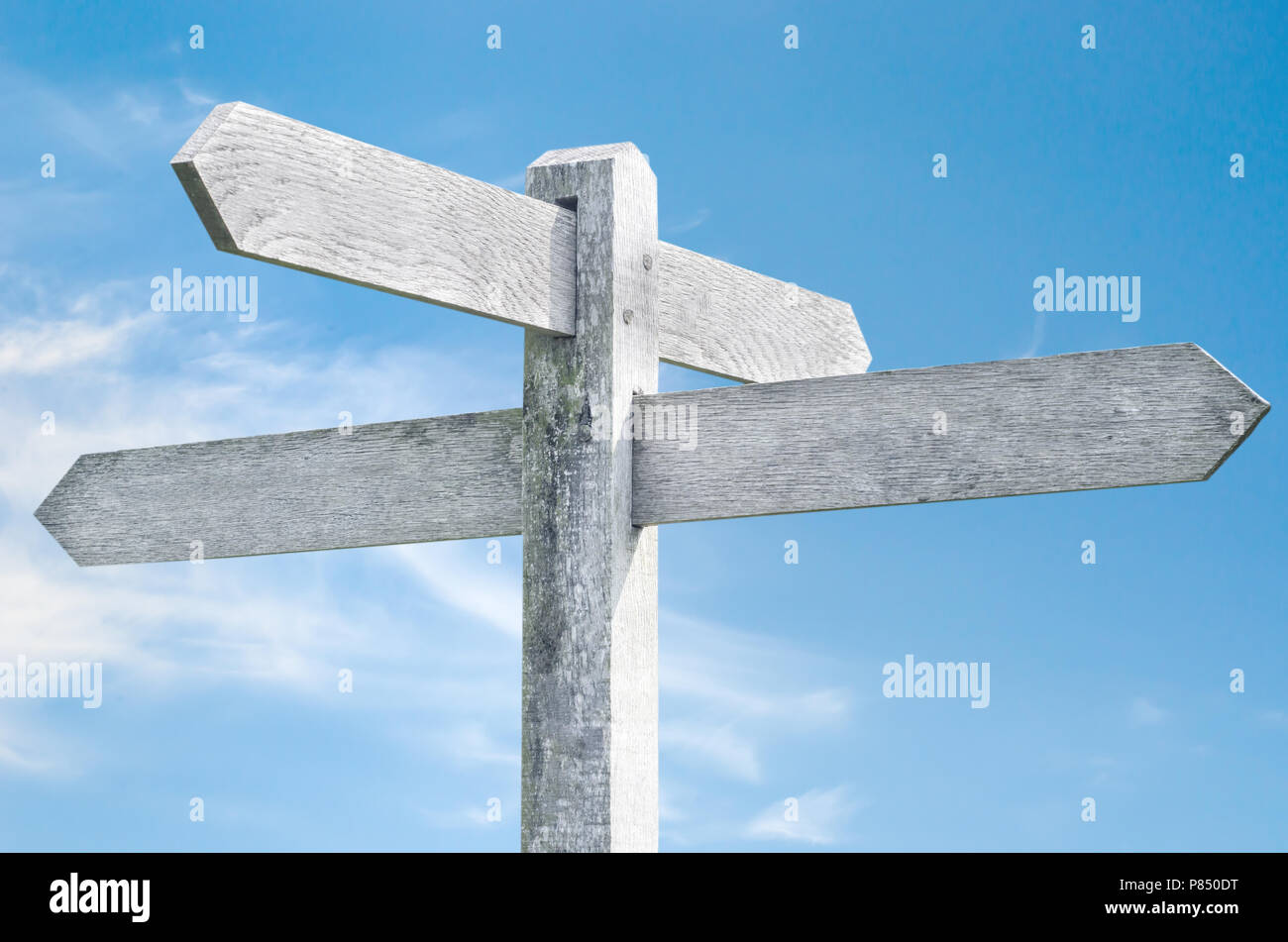 Vecchio weathered indicazioni del cartello in legno contro il cielo blu con quattro scelte di segno rivolte in direzioni differenti. Foto Stock