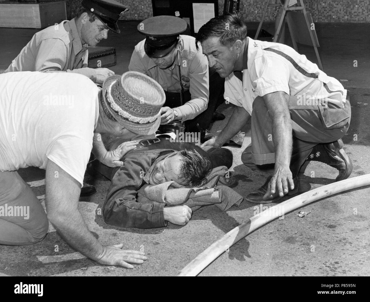 Primi responder aiutare un injuried vigile del fuoco a Kansas City fire scena, ca. 1965. Foto Stock
