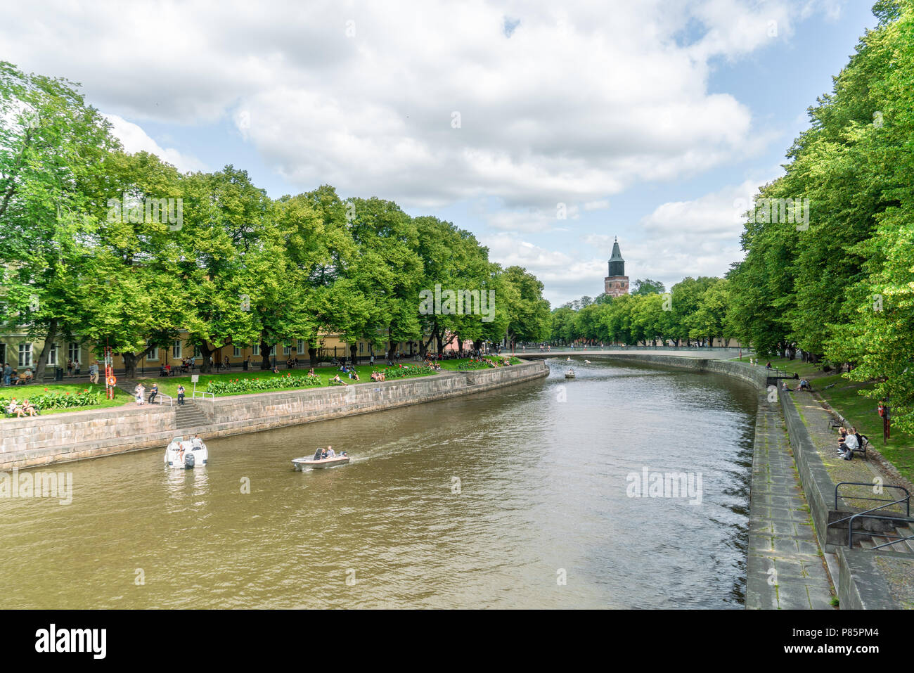 TURKU, Finlandia - 8/7/2018: barche sul fiume Aura su soleggiate giornate estive con torre della cattedrale di Turku in background Foto Stock