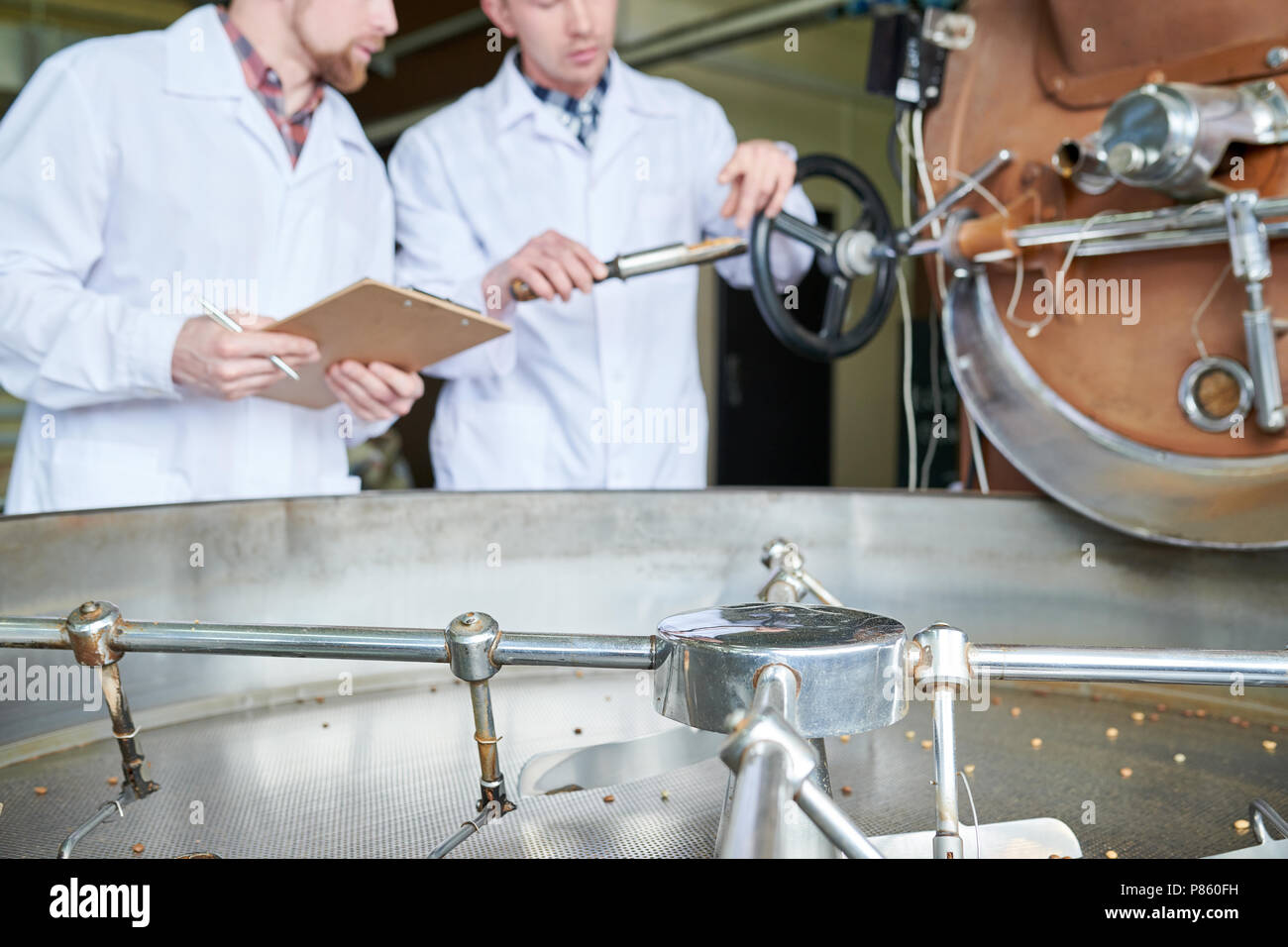 Metà sezione ritratto di due irriconoscibile moderni giovani uomini che indossano camici da laboratorio a discutere di lavorazione del caffè mentre si lavora in roastery, spazio di copia Foto Stock