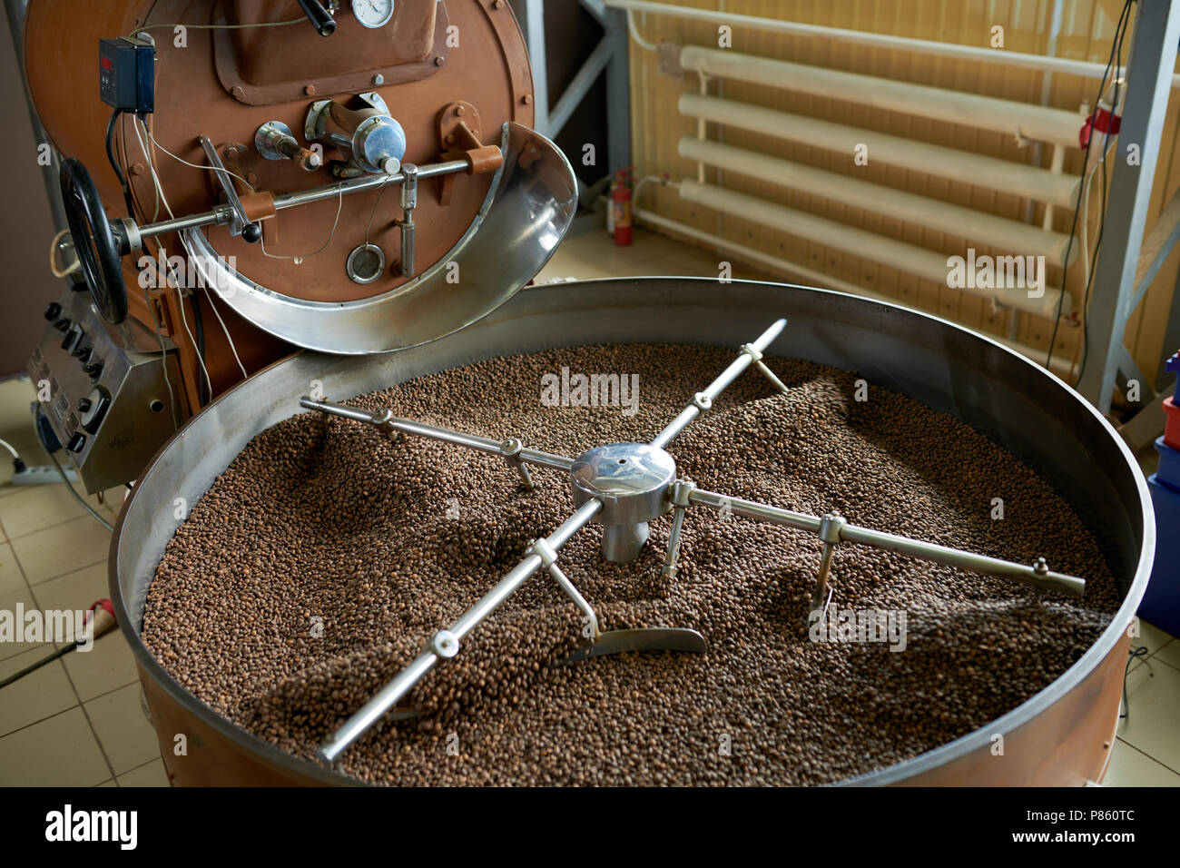 Vista al di sopra del tamburo di moderne macchine di tostatura con fresca bruna i chicchi di caffè in laboratorio di lavorazione del caffè manufactory Foto Stock