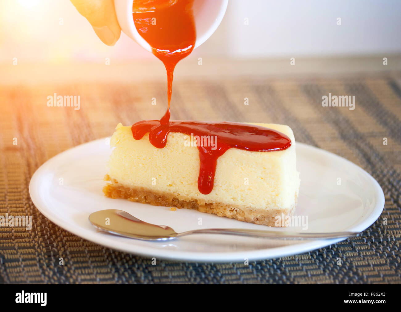 Versare la salsa di fragole in cheesecake, Strawberry Cheesecake , una  cheesecake, cioccolato bianco - Luce solare per effetto del filtro Foto  stock - Alamy