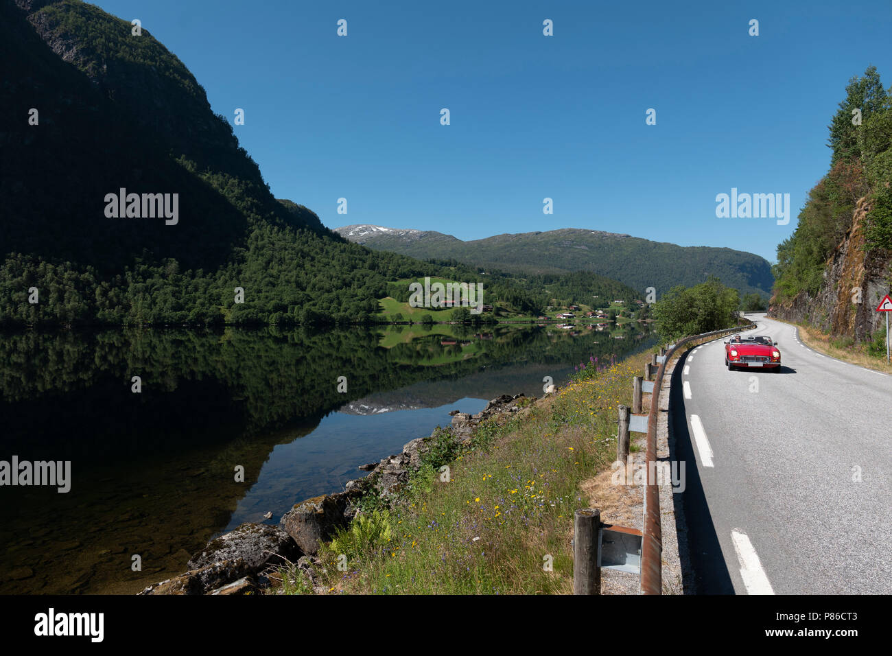 Alla guida di una vettura sportiva rossa sulla bella strada Gaularfjell, Norvegia Foto Stock