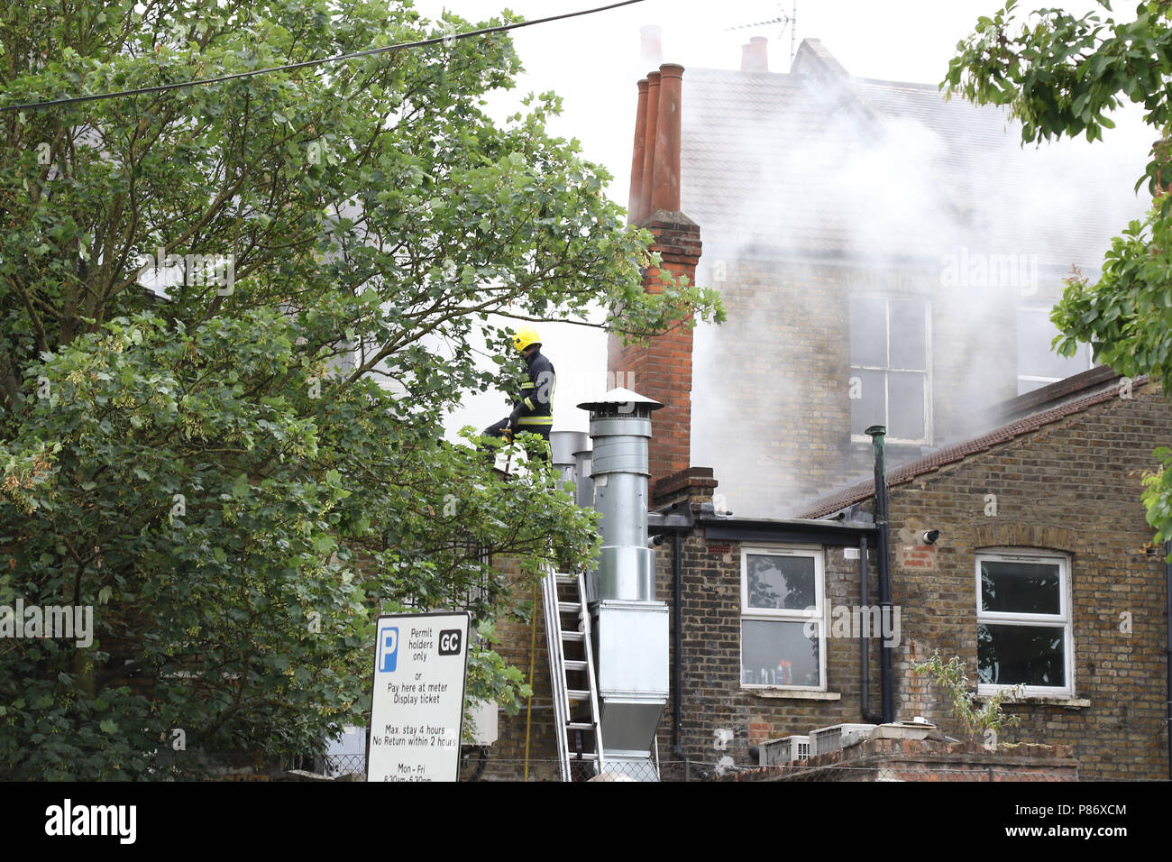 Londra, Regno Unito. Il 10 luglio 2018. Vigili del fuoco combattendo contro un incendio su Willesden High Road mentre poliziotti armati con cani addestrati effettuare un raid e arresti su tre persone nel nord ovest di Londra 10 luglio 2018 Credit: Martin Evans/Alamy Live News Foto Stock