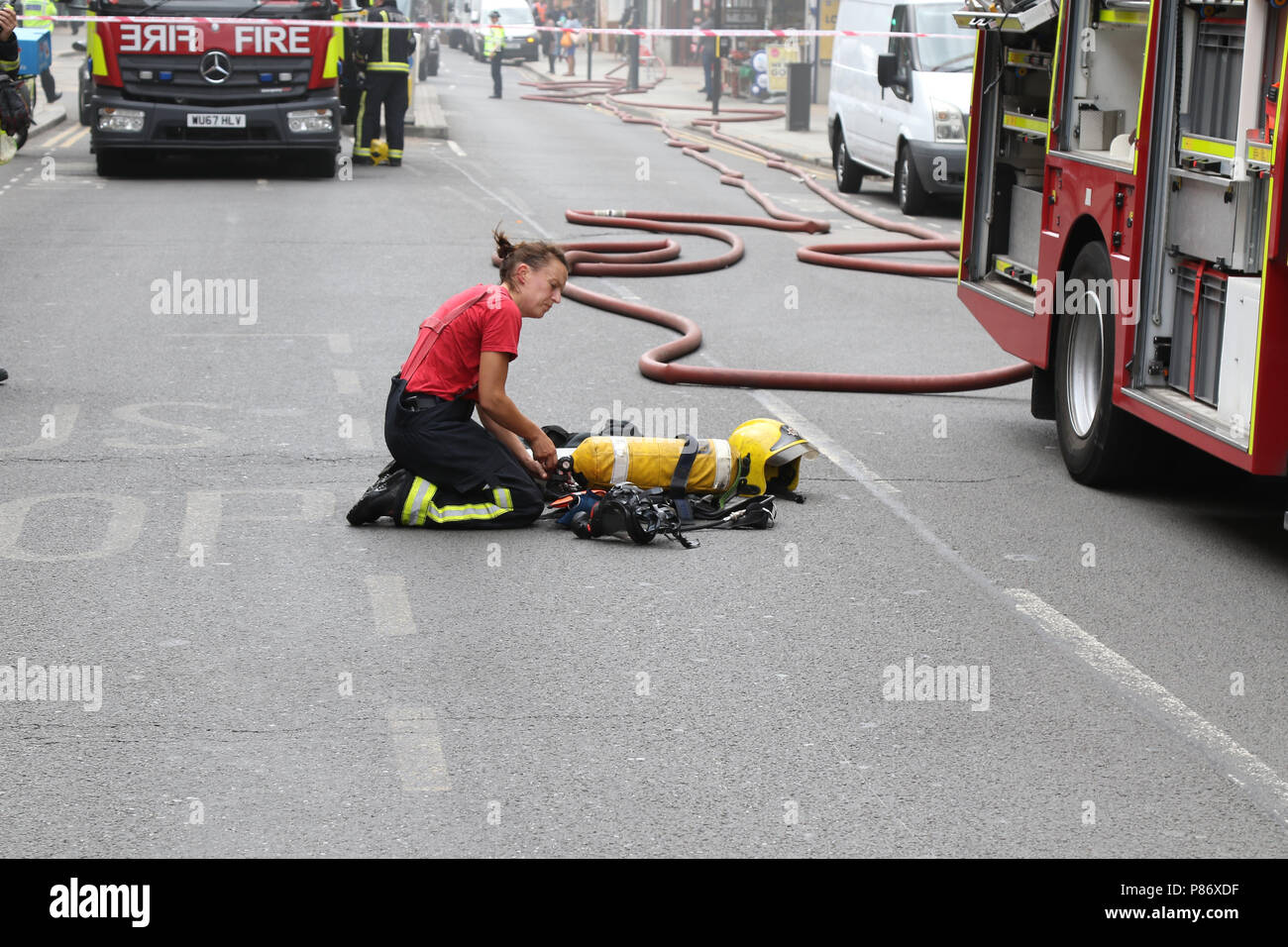 Londra, Regno Unito. Il 10 luglio 2018. Vigili del fuoco combattendo contro un incendio su Willesden High Road mentre poliziotti armati con cani addestrati effettuare un raid e arresti su tre persone nel nord ovest di Londra 10 luglio 2018 Credit: Martin Evans/Alamy Live News Foto Stock