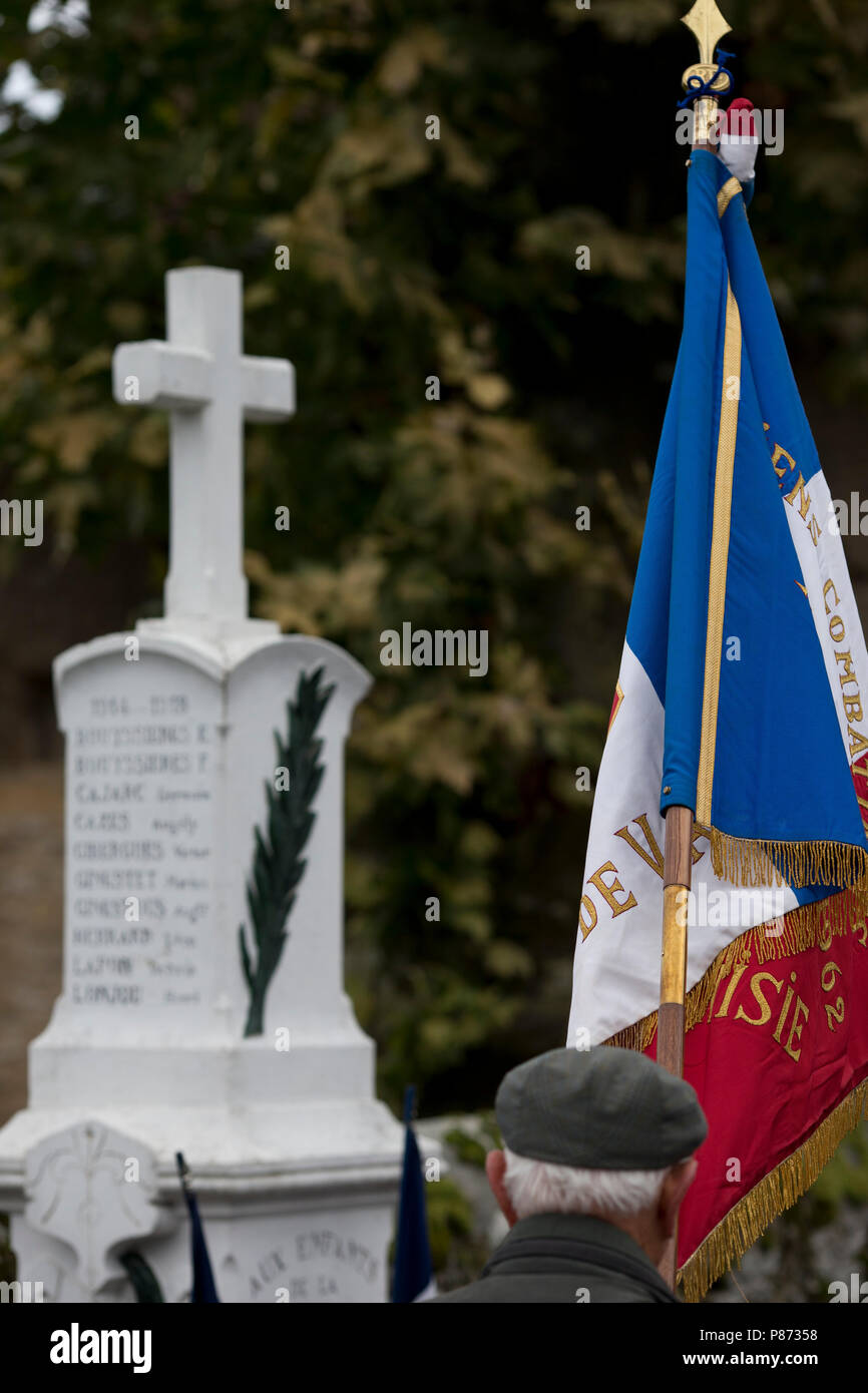 Un veterano francese mantiene la sua bandiera del reggimento il giorno dell'Armistizio prima il memoriale di guerra a San Marziale, Varen, Tarn et Garonne, Occitanie, Francia, Europa Foto Stock