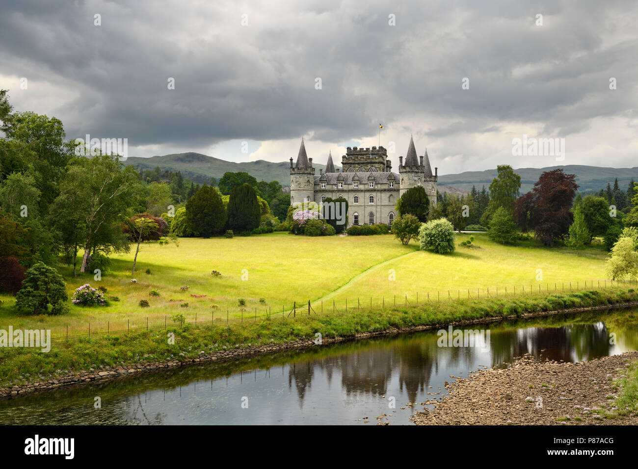 Inveraray Castle riflessa nel fiume Aray con nuvole scure e golden erba nelle Highlands scozzesi Scotland Regno Unito Foto Stock