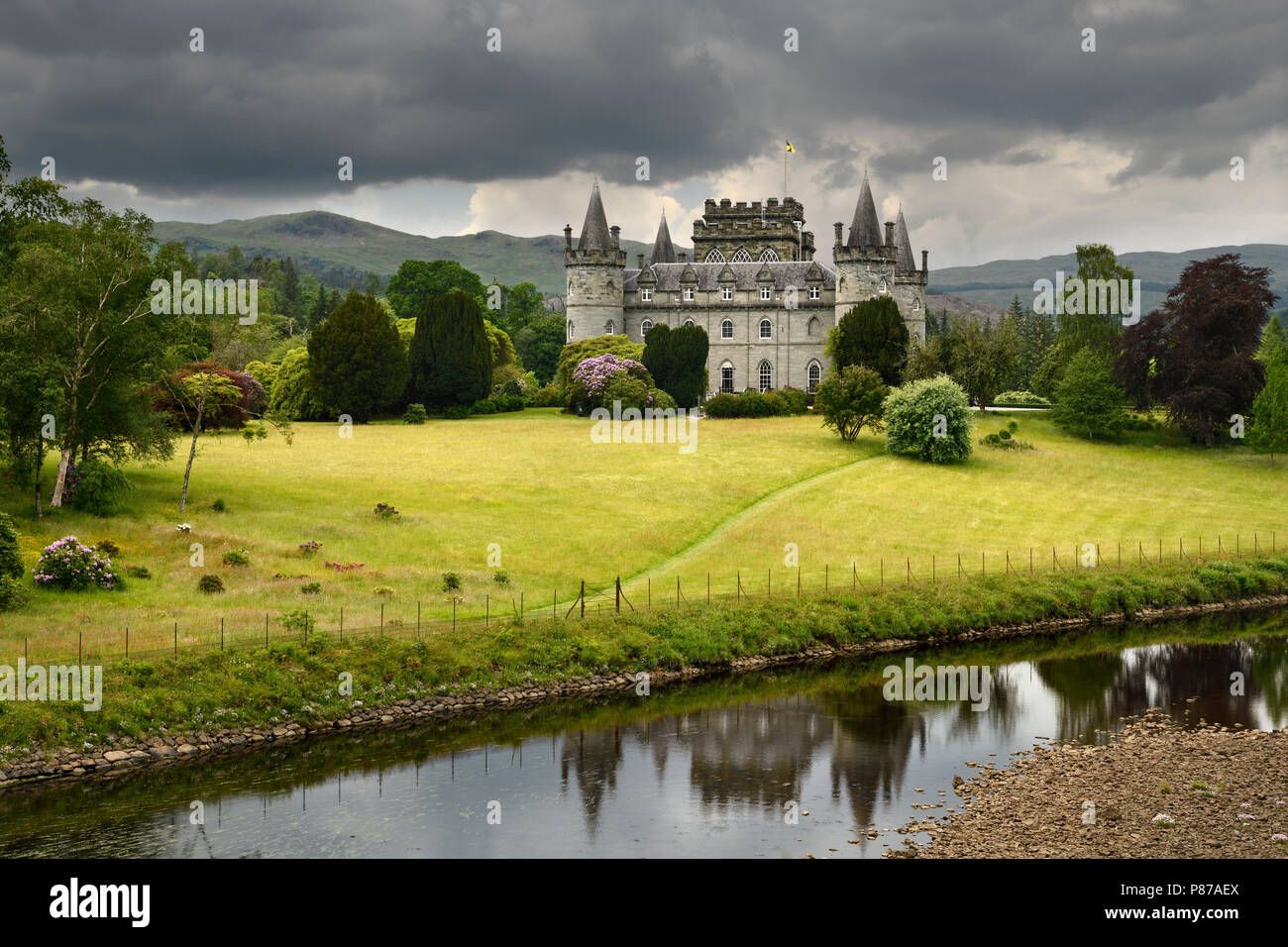 Inveraray Castle riflessa nel fiume Aray a Loch Fyne con nuvole scure e golden erba nelle Highlands scozzesi Scotland Regno Unito Foto Stock