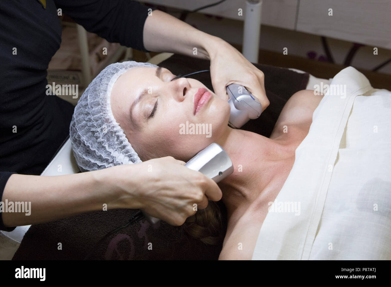 Closeup ritratto di bella donna e la mano con radio cosmetici dispositivo di sollevamento tocchino il suo volto Foto Stock