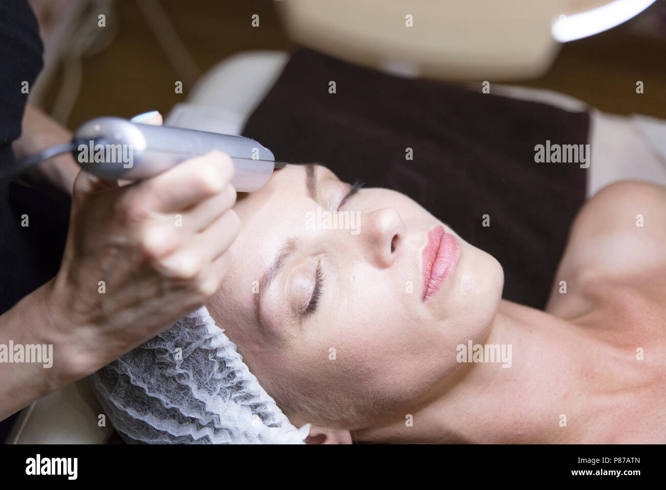 Closeup ritratto di felice giovane donna e la mano con cosmetici dispositivo di sollevamento tocchino il suo volto Foto Stock