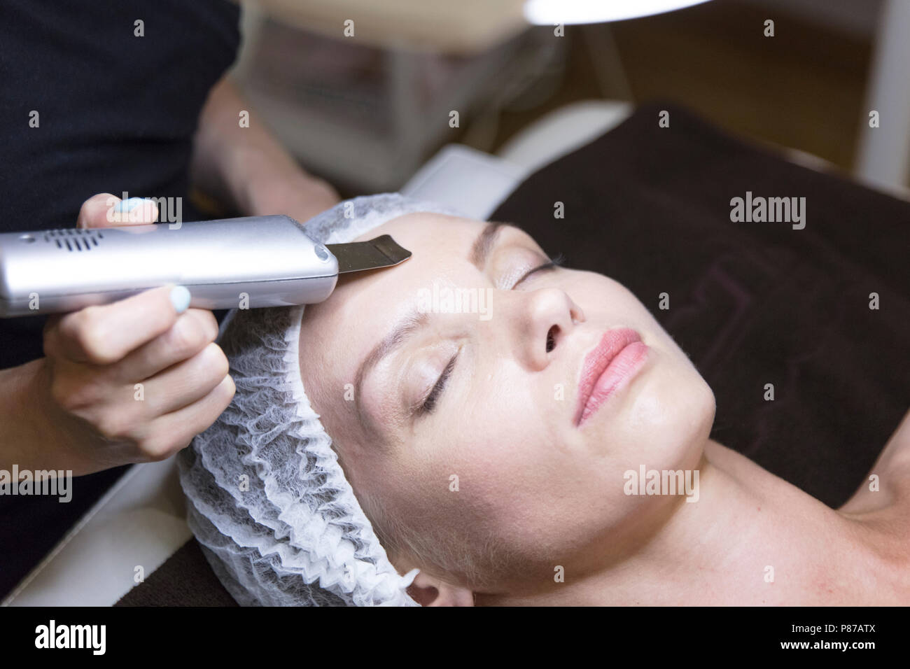 Closeup ritratto di bella donna e la mano con cosmetici dispositivo di sollevamento tocchino il suo volto Foto Stock