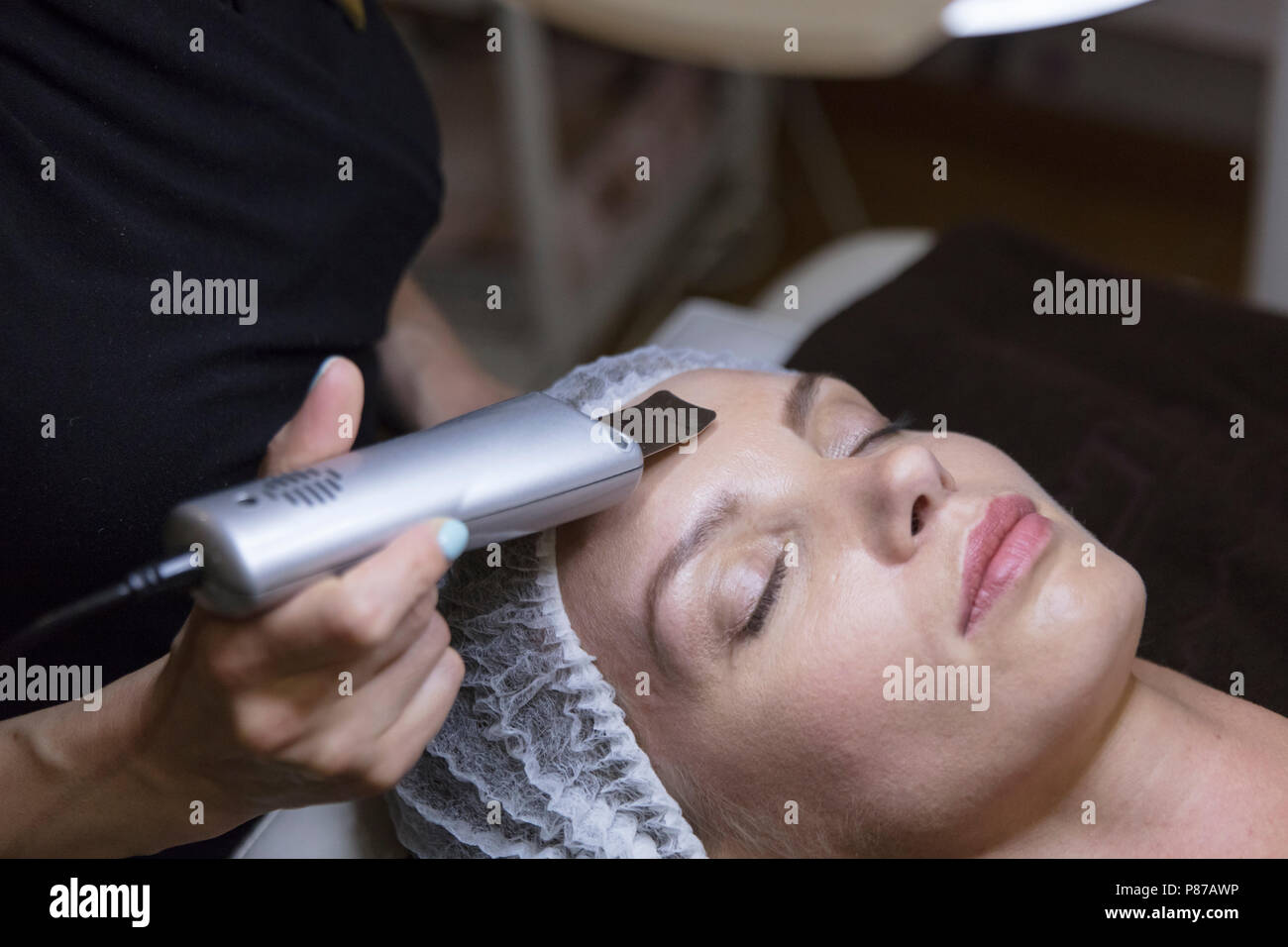 Closeup ritratto di bella donna e la mano con cosmetici dispositivo di sollevamento procedura toccando il suo volto Foto Stock